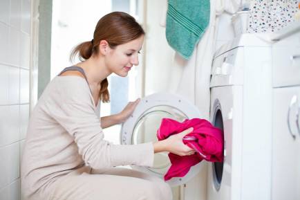 Mujer poniendo ropa en la lavadora